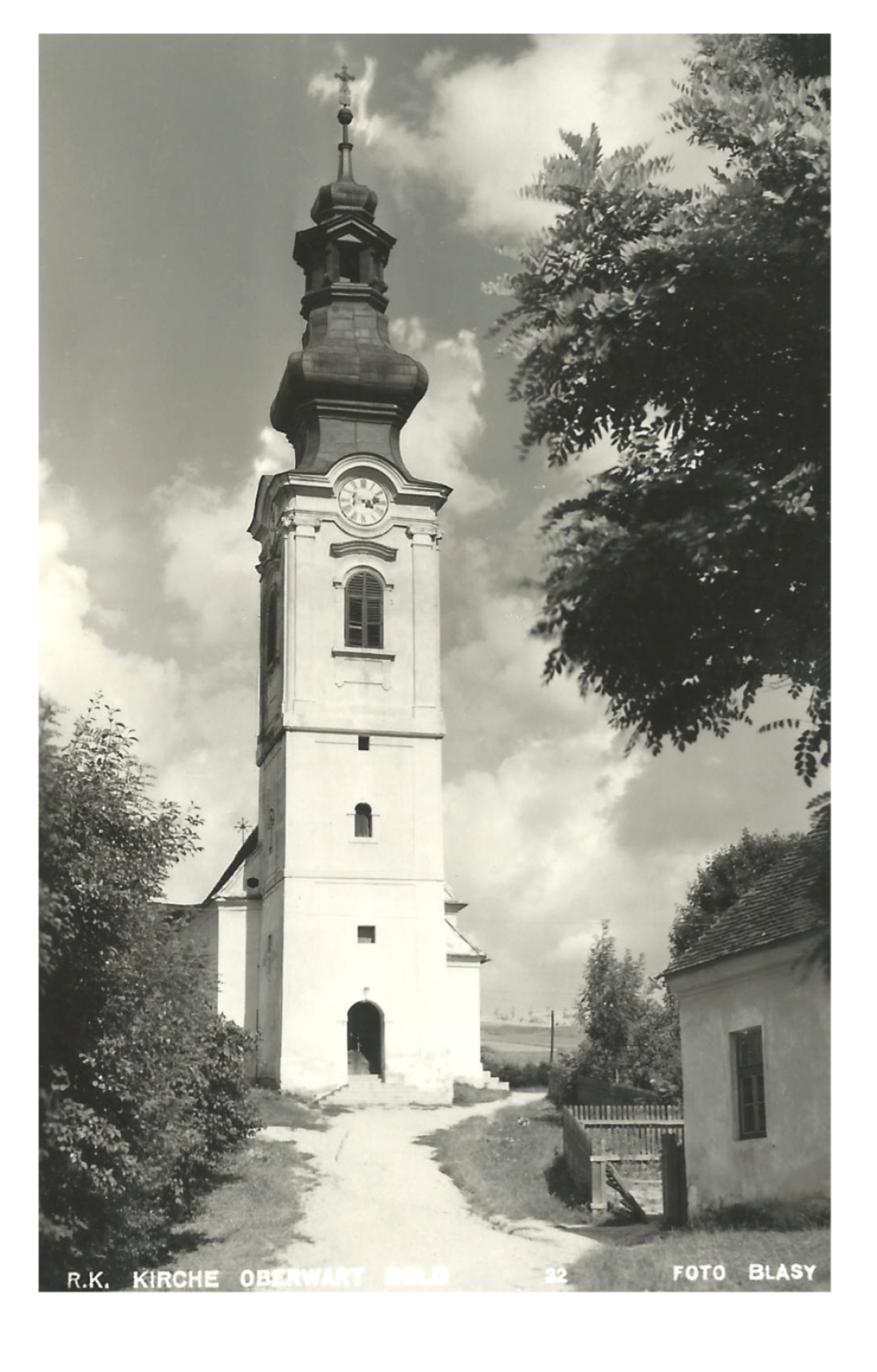 Ansichtskarte: Röm. kath. Pfarrkirche mit Kirchenweg und der nördlichen Hausecke der röm. kath. Schule