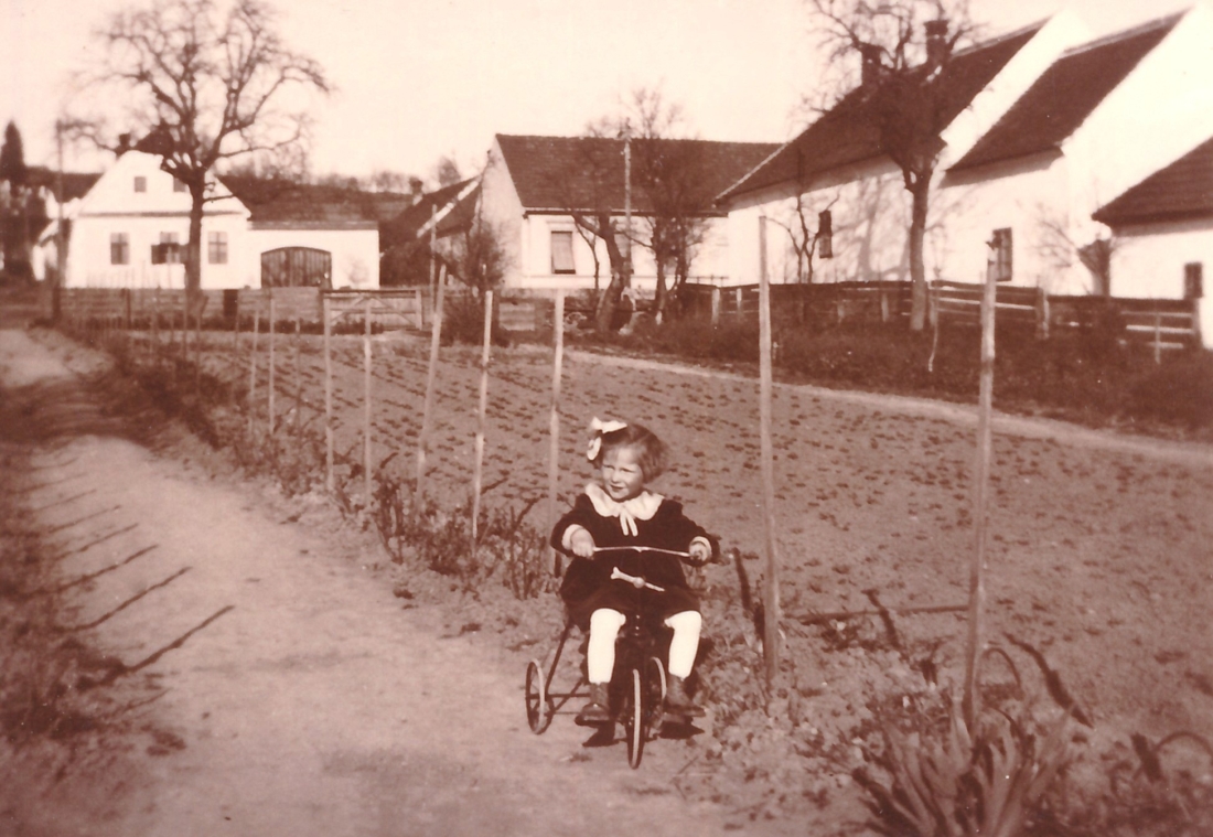 Elfi Graf (verh. Langer, *1936/+2015) auf dem Dreirad in der elterlichen Gärtnerei (Steinamangererstraße 36+38)