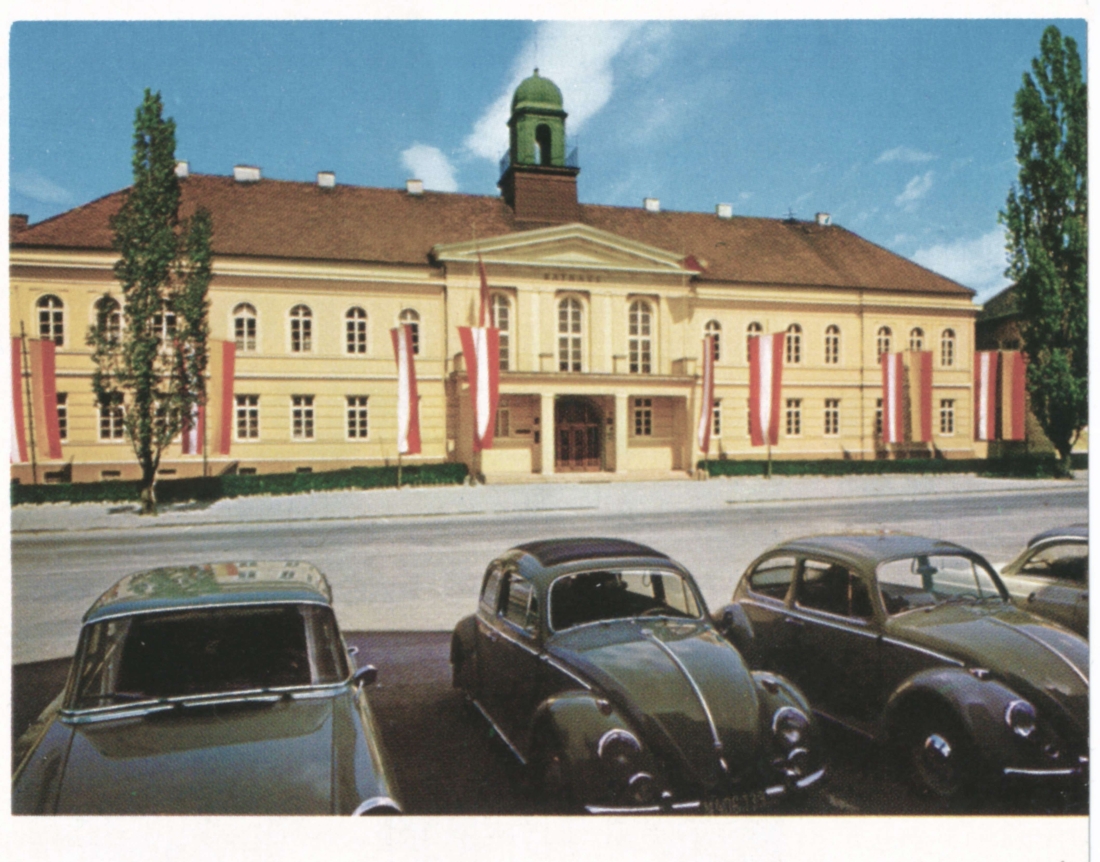 Blick über den Hauptplatz auf das beflaggte Rathaus - Opel/VW-Käfer